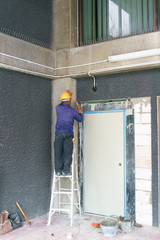 construction worker wearing yellow safety helmet using hammer and chisel to extract the cement on the wall at construction site.