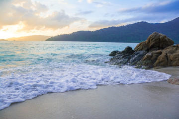 soft waves hit the shore and rock, with sunlighht and beautiful view
