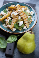 Salad with fresh spinach leaves, grilled pears and feta cheese, selective focus, vertical shot