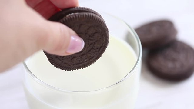 Close up of a woman dunking chocolate cookies in milk