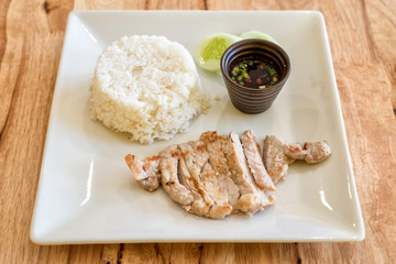 Thai grilled pork neck with spicy dipping sauce served with jasmine rice .