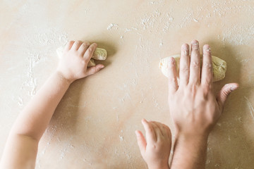 Children's and dad's hands makes raw dough