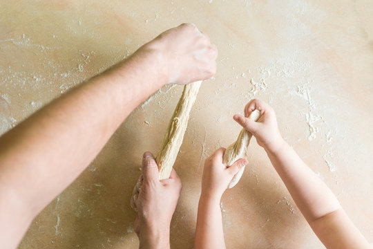Children's and dad's hands makes raw dough