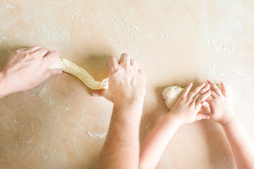 Fototapeta premium Children's and dad's hands makes raw dough