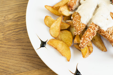 Delicious sesame chicken sticks with potatoes and vegetables. Delicious buttery topping. Beautifully served plate at the restaurant.
