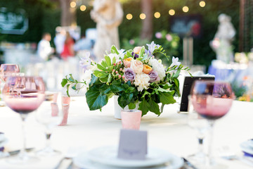 Flower table decorations for holidays and wedding dinner. Table set for holiday, event, party or wedding reception in outdoor restaurant.