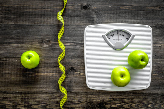 Lose weight concept. Bathroom scale, measuring tape, apples on wooden background top view