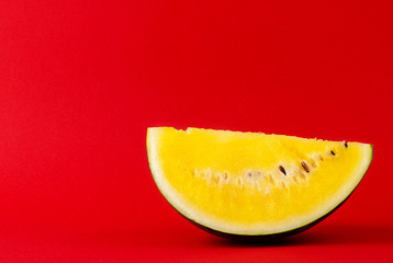 sliced watermelon with yellow flesh on a red background