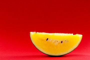 Naklejka na ściany i meble sliced watermelon with yellow flesh on a red background