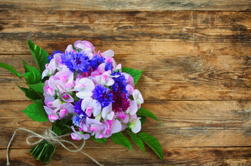 bouquet of cornflowers and sweet peas, on wooden table, vintage style