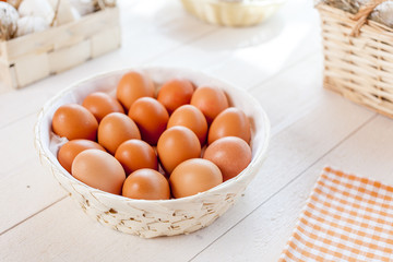Chicken eggs in basket on wooden background