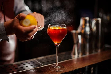 Photo sur Plexiglas Cocktail Bartender is adding lemon zest to the cocktail at bar counter