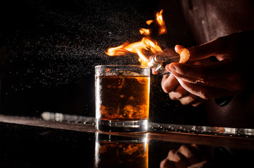 Le barman fait de la flamme au-dessus du cocktail en gros plan