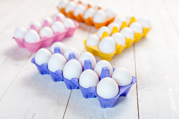 White eggs in colorful boxes on  rustic wooden table, modern concept