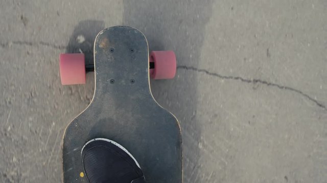 Man riding a longboard, a plan view on the move, close-up, first-person view. Pov view on skateboard and legs