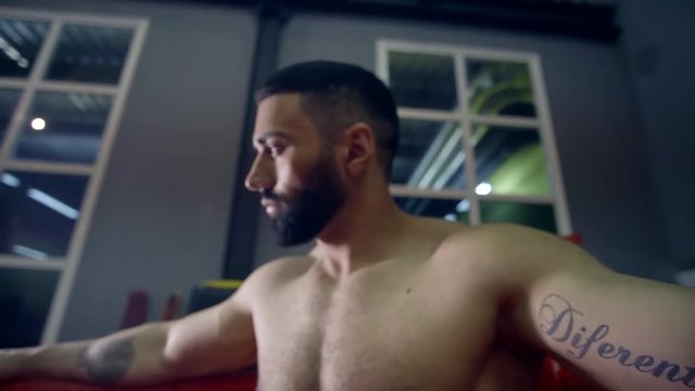muscular heavyweight boxer resting in the corner of the ring leaning back on the ropes