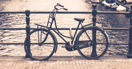 Obraz premium Old bicycle locked on a bridge over water canal, Amsterdam, Netherlands.