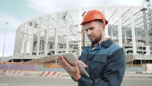 Structure football field, engineer stay in front of soccer arena stadium under construction with tablet PC, architect on work to world cup 2018