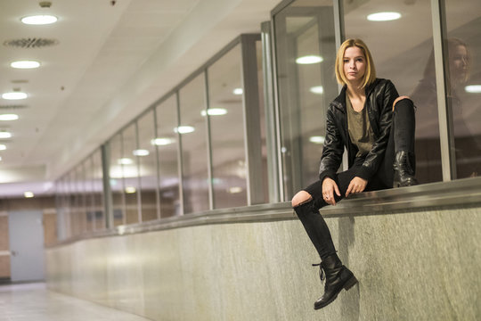 Caucasian woman sitting on ledge of window in corridor