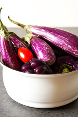 Small eggplants, tomatoes. Dark background. Vegetarian food from the village.