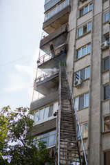 Obraz na płótnie Canvas Firefighters climb the fire escape to extinguish fire on the upper floors of residential building.