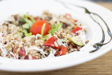 Fragrant Pilau/Pulav / pilaf /pilaf, fried rice with meat and vegetables on a white plate. Isolated on a wooden table.