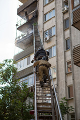 Firefighters climb the fire escape to extinguish fire on the upper floors of residential building.
