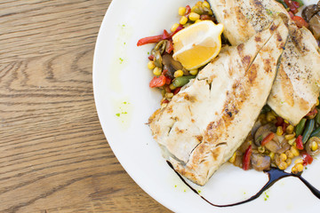 Grill chicken breast. Grilled vegetables with chicken breast. Grilled chicken with vegetables on oak table.