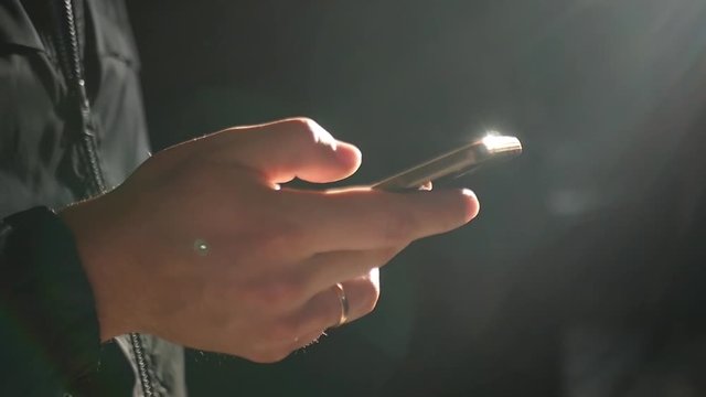 Phone in male hands close-up with glare from the sun, and rays from the window. slow motion. 1920x1080. full hd