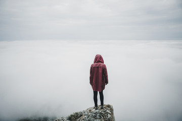 Woman standing on rock and looking at fog
