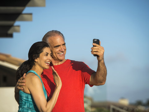 Older couple waving and posing for cell phone selfie