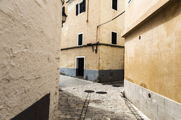 Narrow crossroad on a urban cobble stone street in Menorca, Spain
