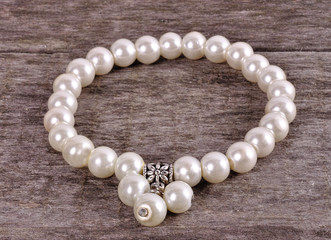 White bracelet with artificial beads on a wooden background