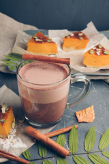 Pumpkin mini cakes on a blue plate. Slice of tasty homemade pie on baking paper.  Cup of hot chocolate