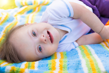 Portrait of Cute baby boy with Down syndrome lying on blanket in summer day on nature © dtatiana