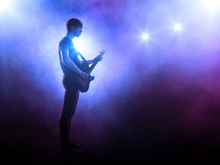 Silhouette of guitar player on stage playing solo