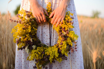 beautiful girl in wreath of flowers in meadow on sunny day. Portrait of Young beautiful woman wearing a wreath of wild flowers. Young pagan Slavic girl conduct ceremony on Midsummer. Earth Day © cinana