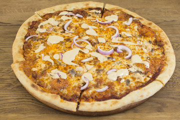 Hot pizza with melting cheese on a rustic wooden table. Delicious meal in the restaurant.