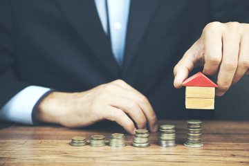 man putting stack of coins with house