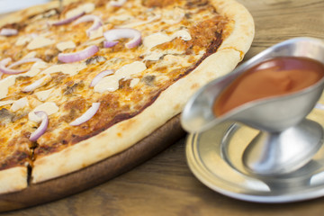 Hot pizza with melting cheese on a rustic wooden table. Delicious meal in the restaurant.