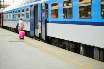 blue grey train with opened door and woman with pink suitcase