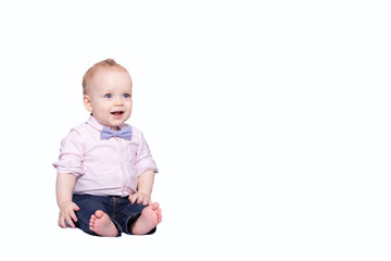 Cute infant boy in a pink shirt and a bow-tie sitting on the white background and looking at camera. Copy space