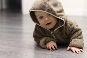 Cute 9 month child in brown fur hoody makes along arm for something