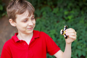 Happy smiling boy playing with fidget spinner, cropped portrait. Childhood, gadgets, entertainment concept