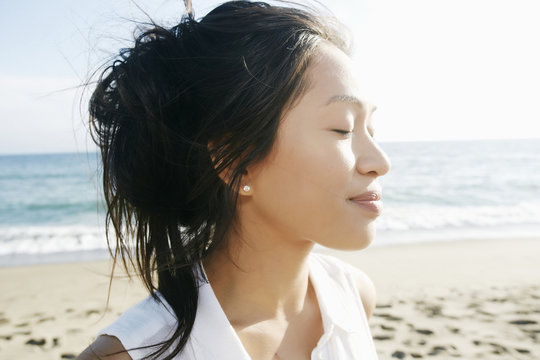 Portrait of Vietnamese woman at beach with eyes closed
