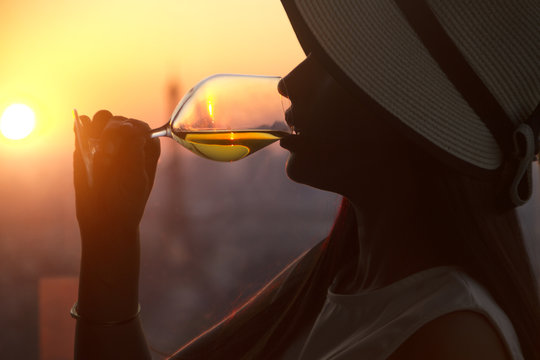 Girl drinking white wine at the sunset in paris city