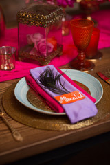 A table set with plate decorate in purple and pink