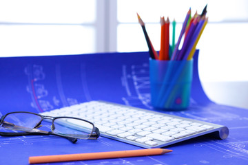 Architectural blueprints and blueprint rolls and a drawing instruments on the worktable
