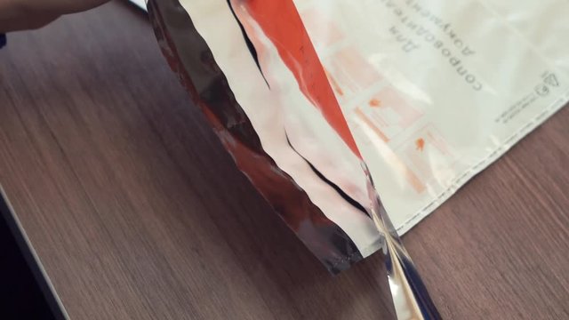 Unrecognisable woman hands in blue sweater peel adhesive line off plastic envelope in office
