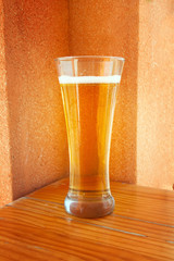 a glass of fresh foaming beer on a wooden table